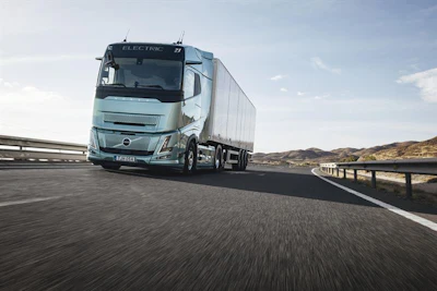 Volvo electric truck driving on highway with white trailer in daylight