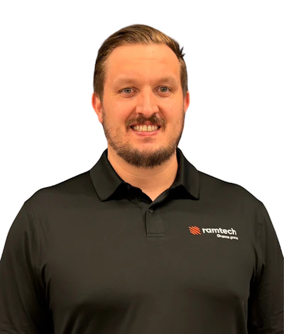 Professional man in black Ramtech polo shirt smiling at camera against white background