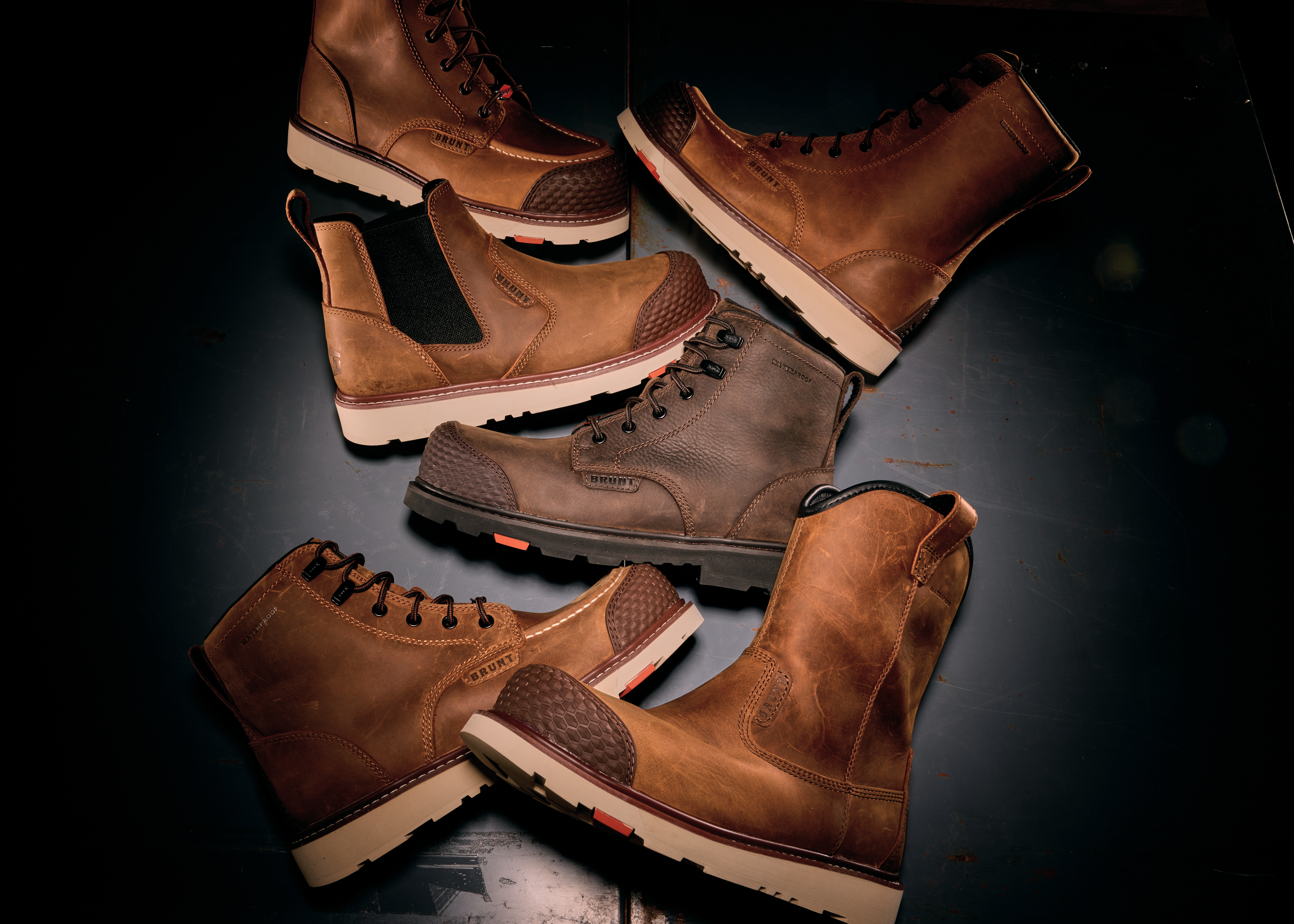Collection of brown leather work boots with cream and tan soles arranged on dark surface
