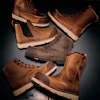 Collection of brown leather work boots with cream and tan soles arranged on dark surface