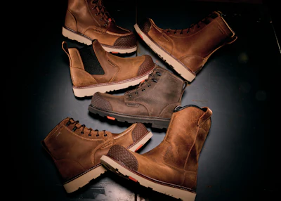 Collection of brown leather work boots with cream and tan soles arranged on dark surface