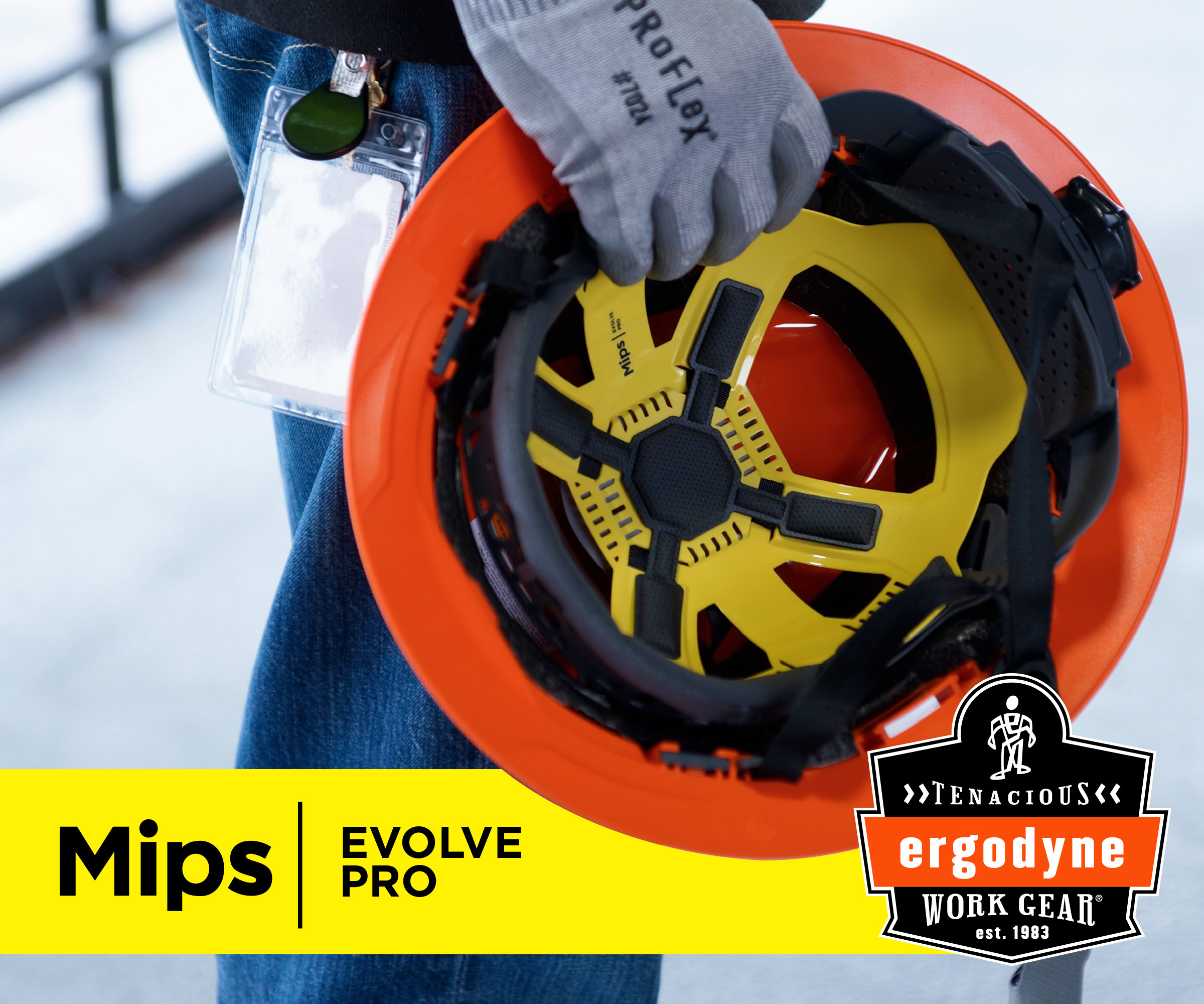 Worker holding orange and yellow MIPS Evolve Pro safety helmet with protective gear and ID badge