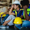 Construction workers in safety vests and hard hats discussing plans on a job site