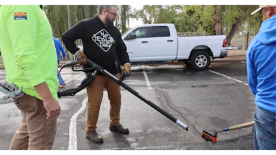 Community volunteers perform parking lot maintenance work during an outdoor service event