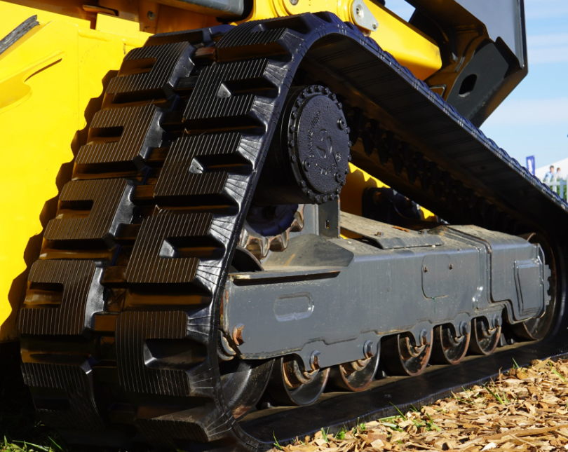 Yellow and gray tracked excavator with large metal treads and hydraulic arm on construction site