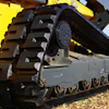 Yellow and gray tracked excavator with large metal treads and hydraulic arm on construction site