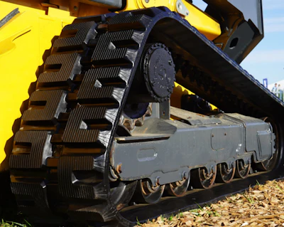 Yellow and gray tracked excavator with large metal treads and hydraulic arm on construction site