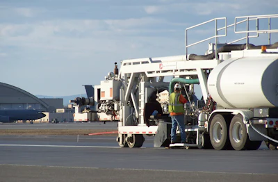Airport ground crew servicing aircraft with fuel tanker and catering vehicles on tarmac