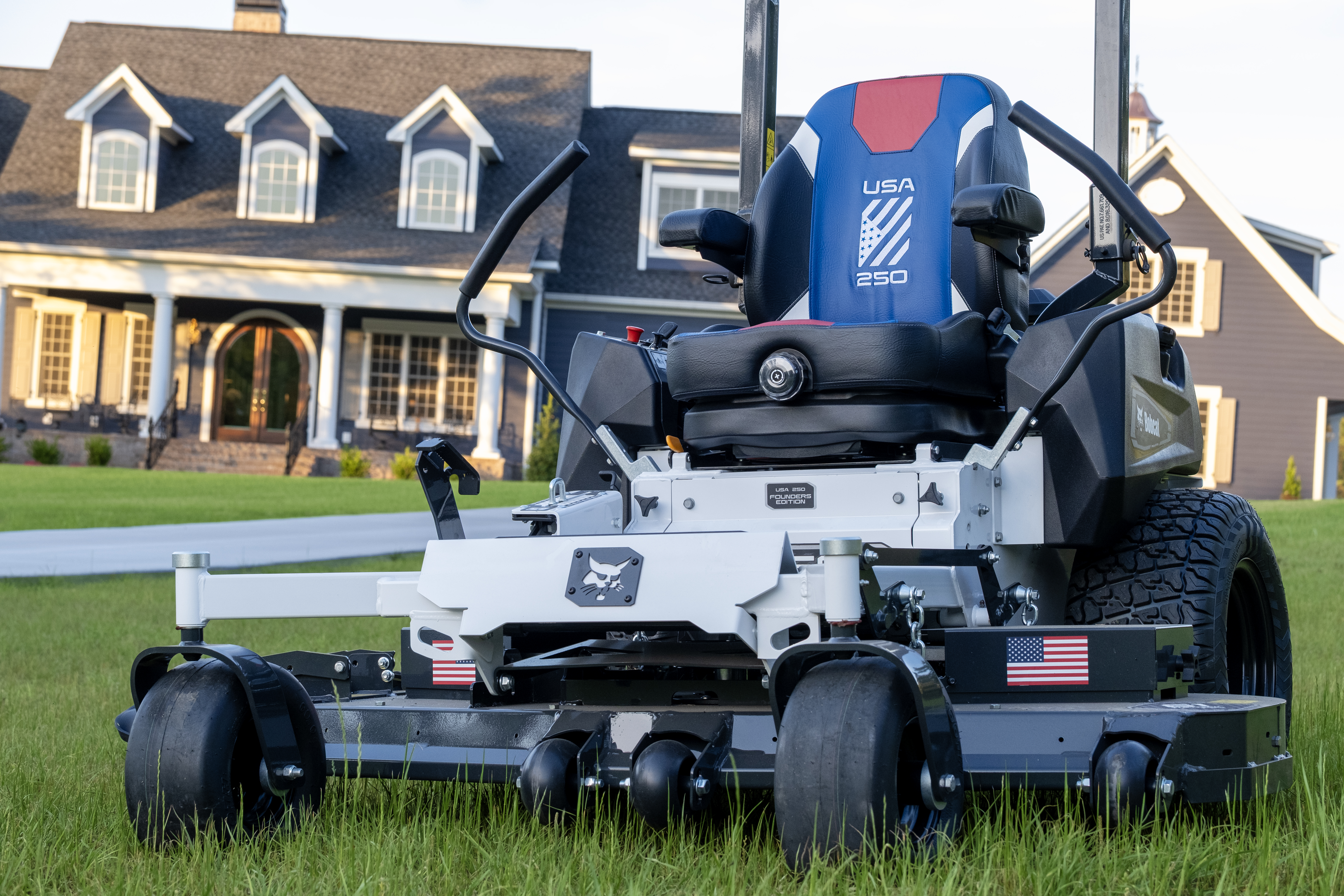 White and black zero-turn radius mower with blue USA branding on residential lawn