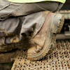 Worker in mud-caked boots and jeans standing on industrial textured surface