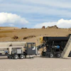 Mobile asphalt mixing plant and paving equipment on construction site with desert landscape