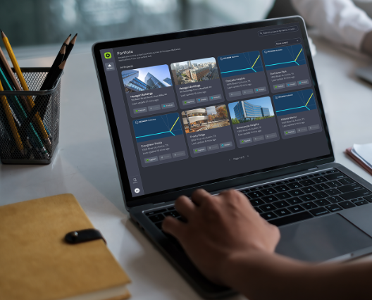 Designer working on laptop displaying portfolio gallery with architectural images in modern workspace