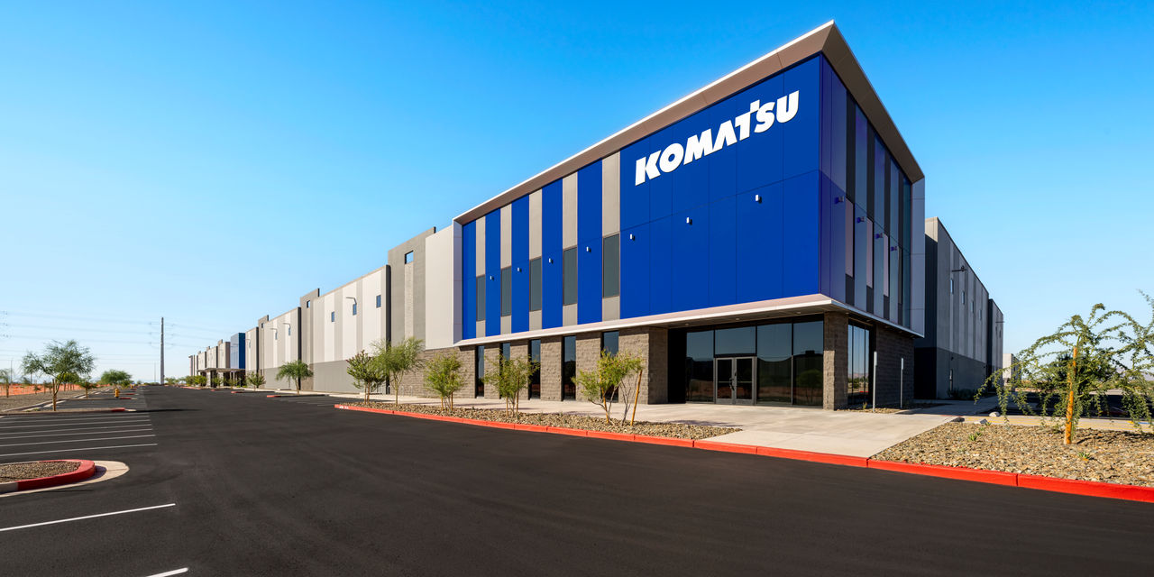 Modern Komatsu industrial facility with blue and white striped facade under clear blue sky