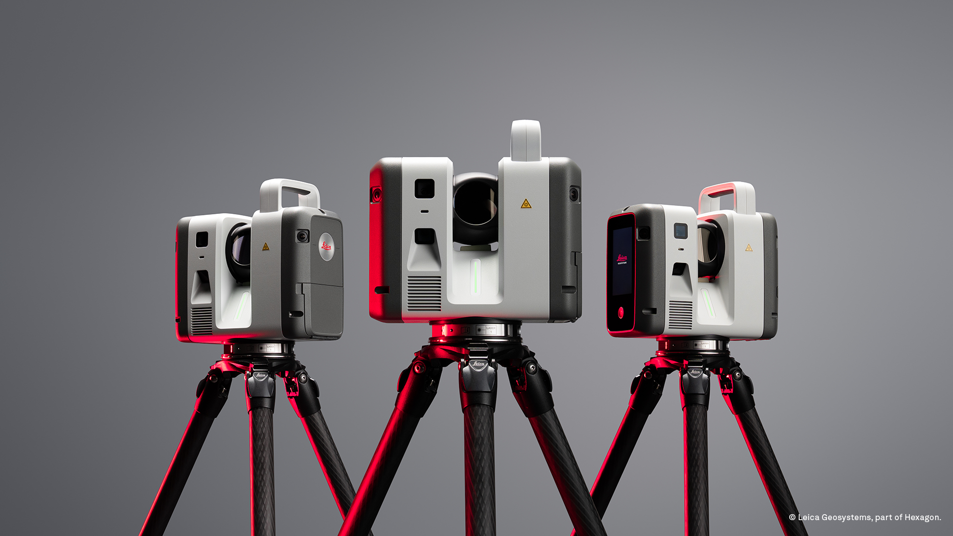 Three Leica laser scanning devices mounted on red tripods against gray background