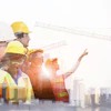 Construction workers in safety gear overlaid on urban skyline with cranes and buildings under development