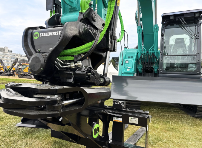 Steelwrist rotating coupling attachment on display with heavy construction equipment and machinery in background