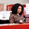 Professional woman working at desk with laptop, surrounded by asset management and notification interface windows in modern office setting
