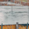 Wet concrete foundation with temporary metal fencing at active construction site