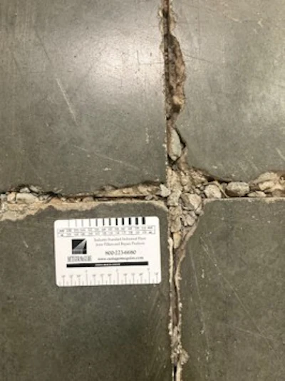 Concrete surface with vertical crack and measurement scale card for documentation