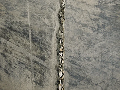 Vertical crack running through gray concrete surface with weathered texture