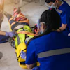 Emergency rescue team performing first aid training with multiple personnel in blue uniforms and safety equipment