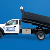 White Hilltip dump truck with raised black bed against blue background