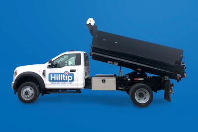 White Hilltip dump truck with raised black bed against blue background