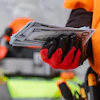Person in orange winter jacket holding Euro banknotes with red and black gloves outdoors