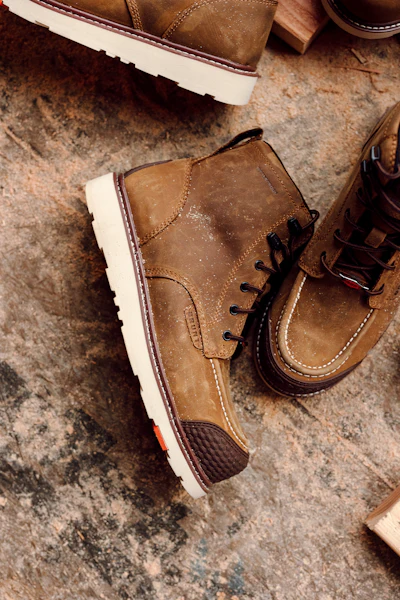 Tan suede chukka boots with white crepe soles and black laces displayed on concrete surface