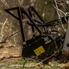 Black snow blower with yellow warning label clearing branches in forest setting