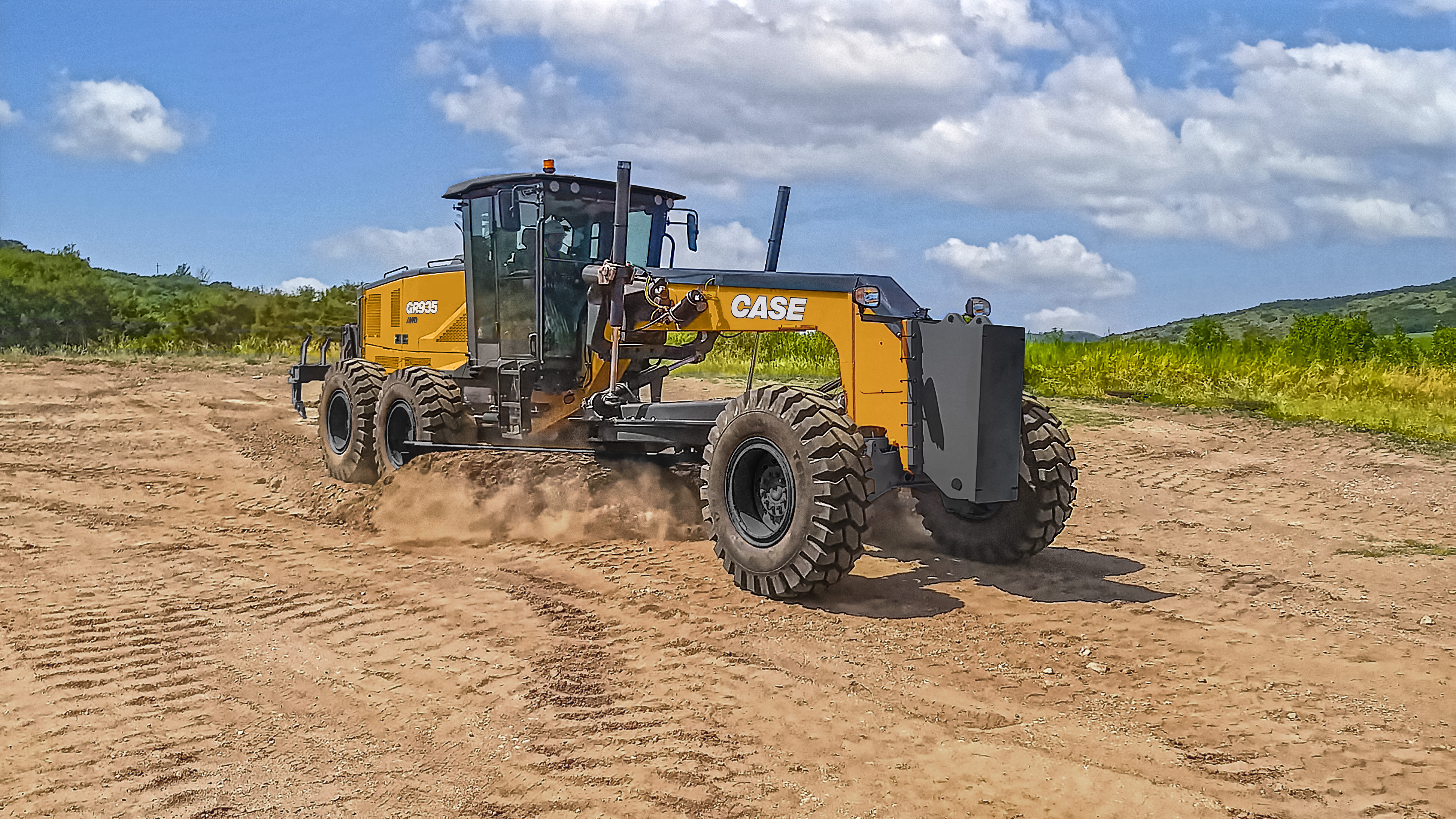 Yellow CASE motor grader operating on dirt road with green landscape and blue sky