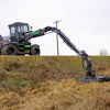 Black and green telescopic handler with extended boom operating in harvested field near power lines