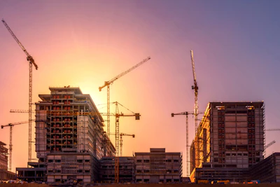 Construction site at sunset with multiple cranes and high-rise buildings under development