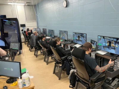 Gaming facility with multiple players seated at computer workstations in a light-filled room with blue-tiled walls
