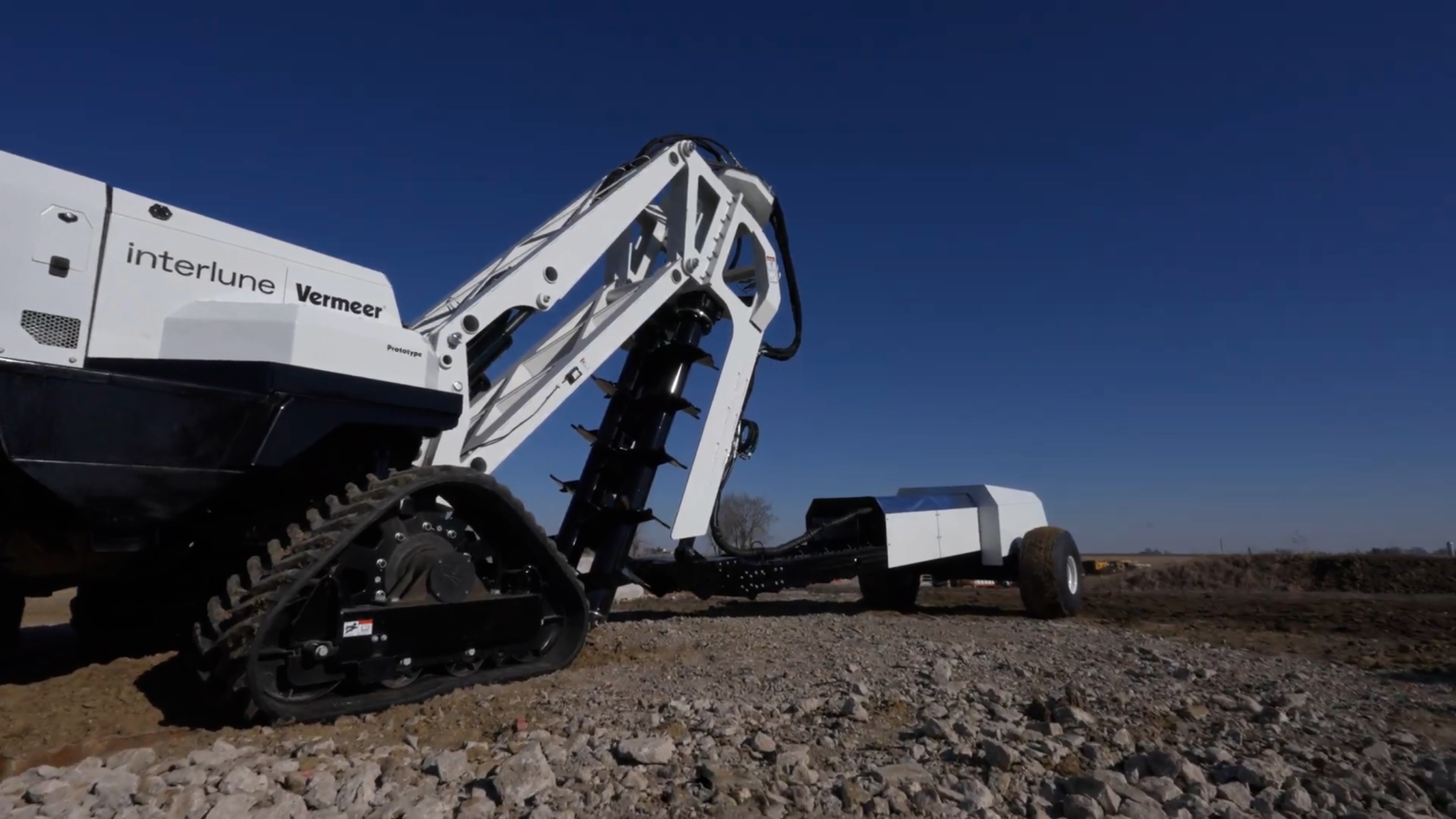 White Vermeer Interlune tracked skid steer loader on gravel ground under clear blue sky