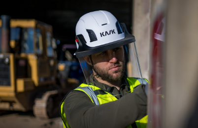Construction worker wearing white KASK safety helmet with yellow-green reflective vest on industrial job site
