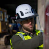 Construction worker wearing white KASK safety helmet with yellow-green reflective vest on industrial job site
