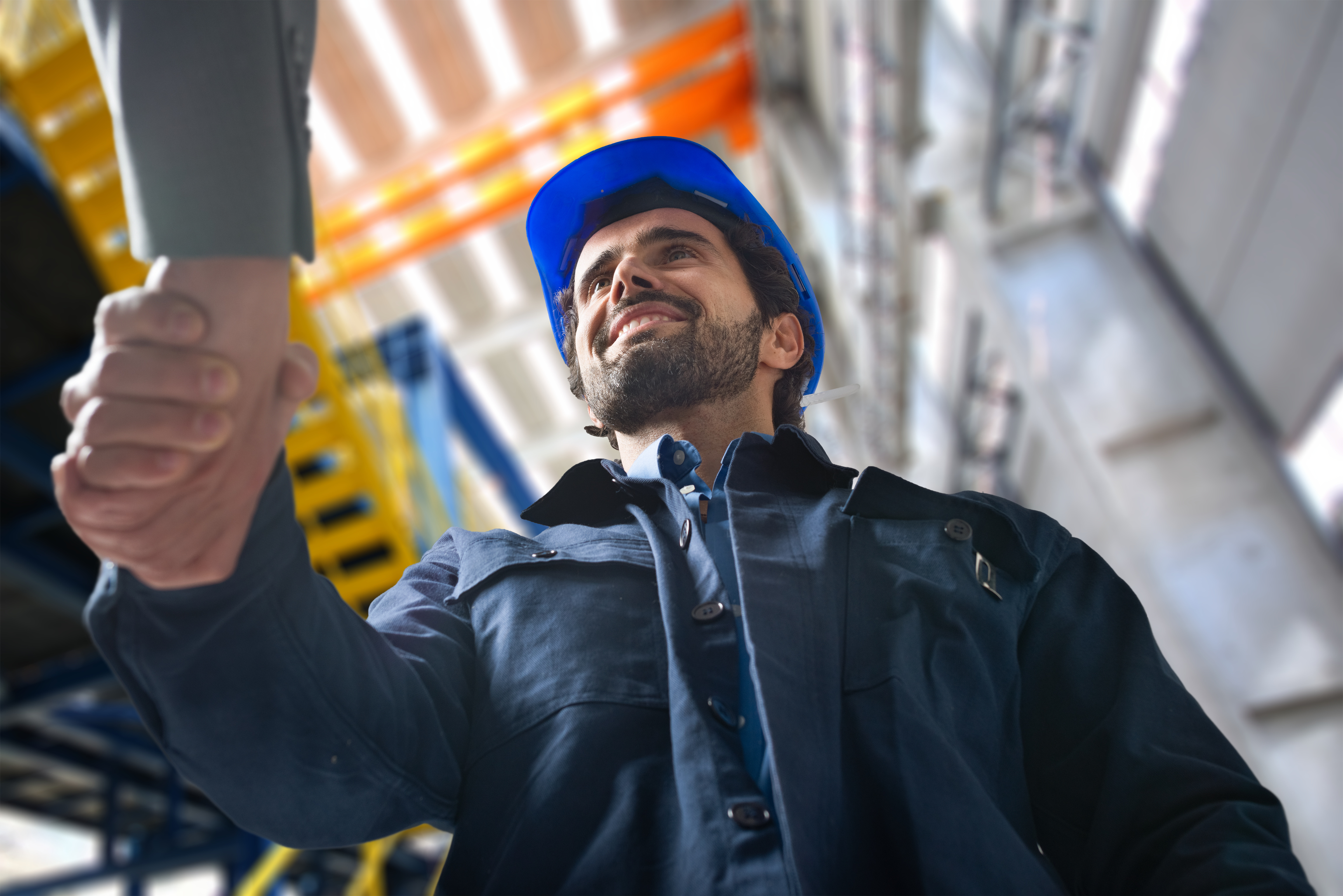Construction worker in blue hard hat looking upward on industrial job site