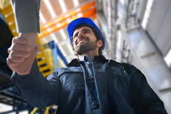 Construction worker in blue hard hat looking upward on industrial job site