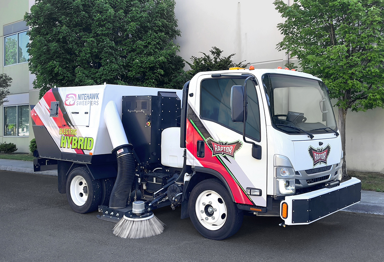 White and red Nilfisk Hybrid street sweeper truck with rotating brush mechanism parked on asphalt