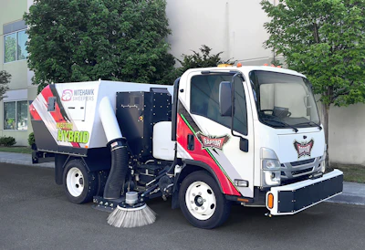 White and red Nilfisk Hybrid street sweeper truck with rotating brush mechanism parked on asphalt