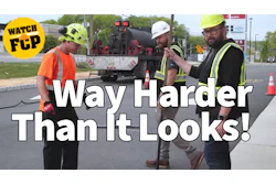 Construction workers in safety gear discussing road work project with equipment truck in background