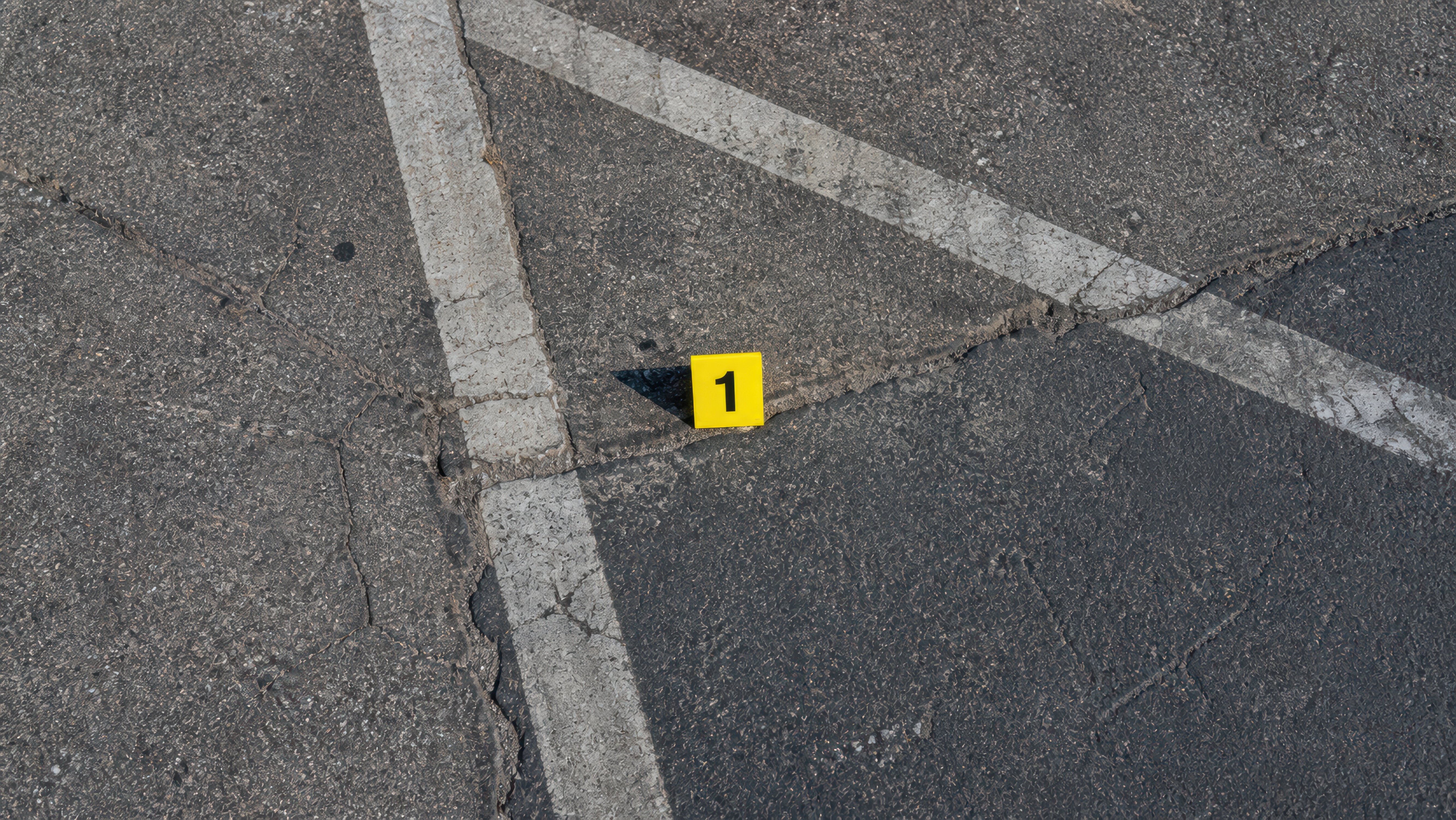 Yellow evidence marker numbered 1 on asphalt with white painted lines