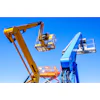 Yellow and blue aerial work platforms with extended booms and safety baskets against clear blue sky