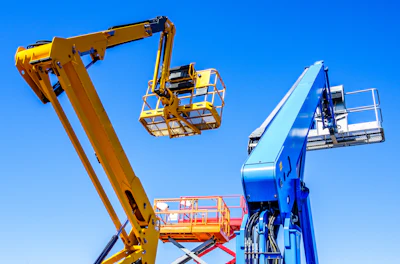 Yellow and blue aerial work platforms with extended booms and safety baskets against clear blue sky