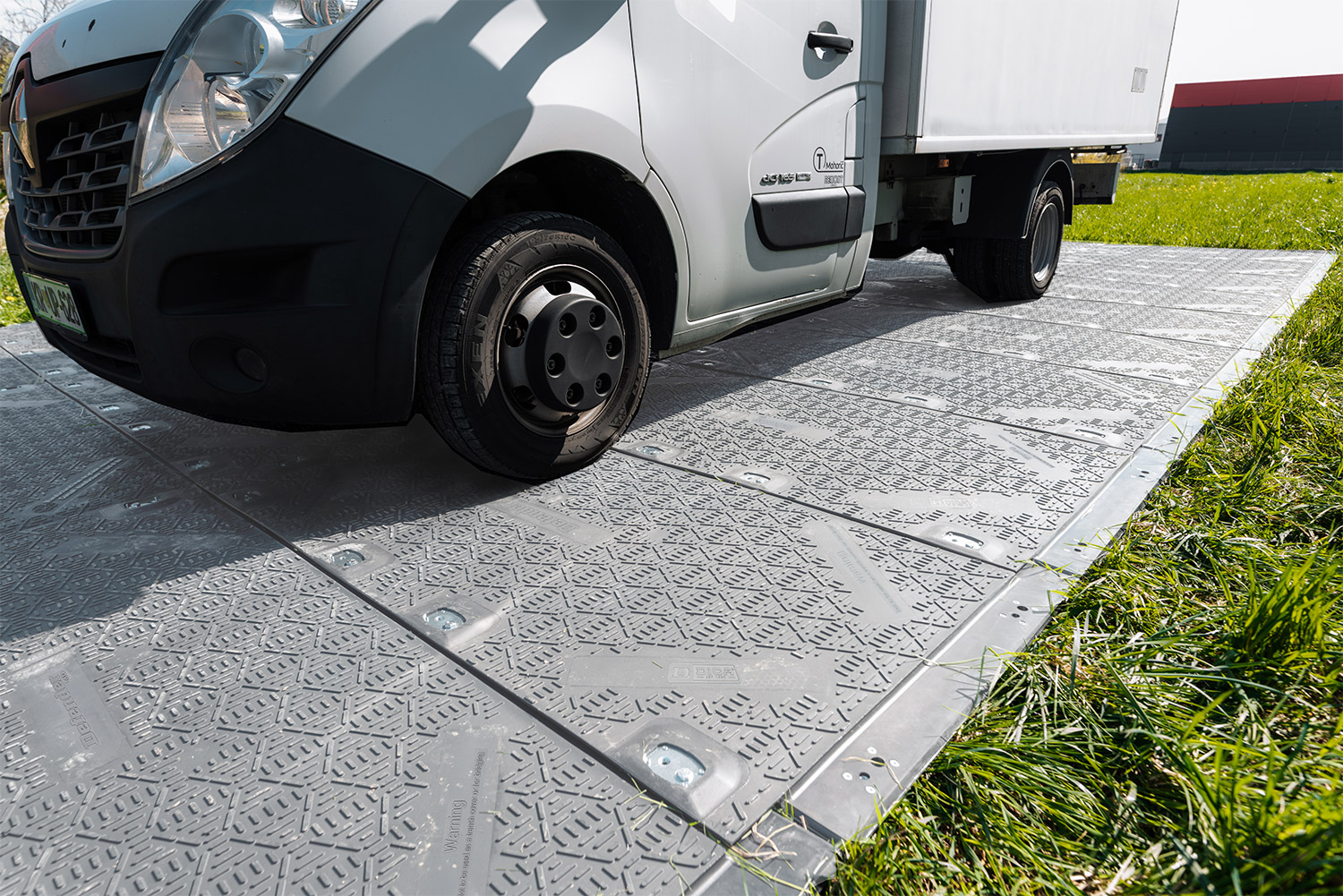 White commercial delivery van parked on textured paving with grass border