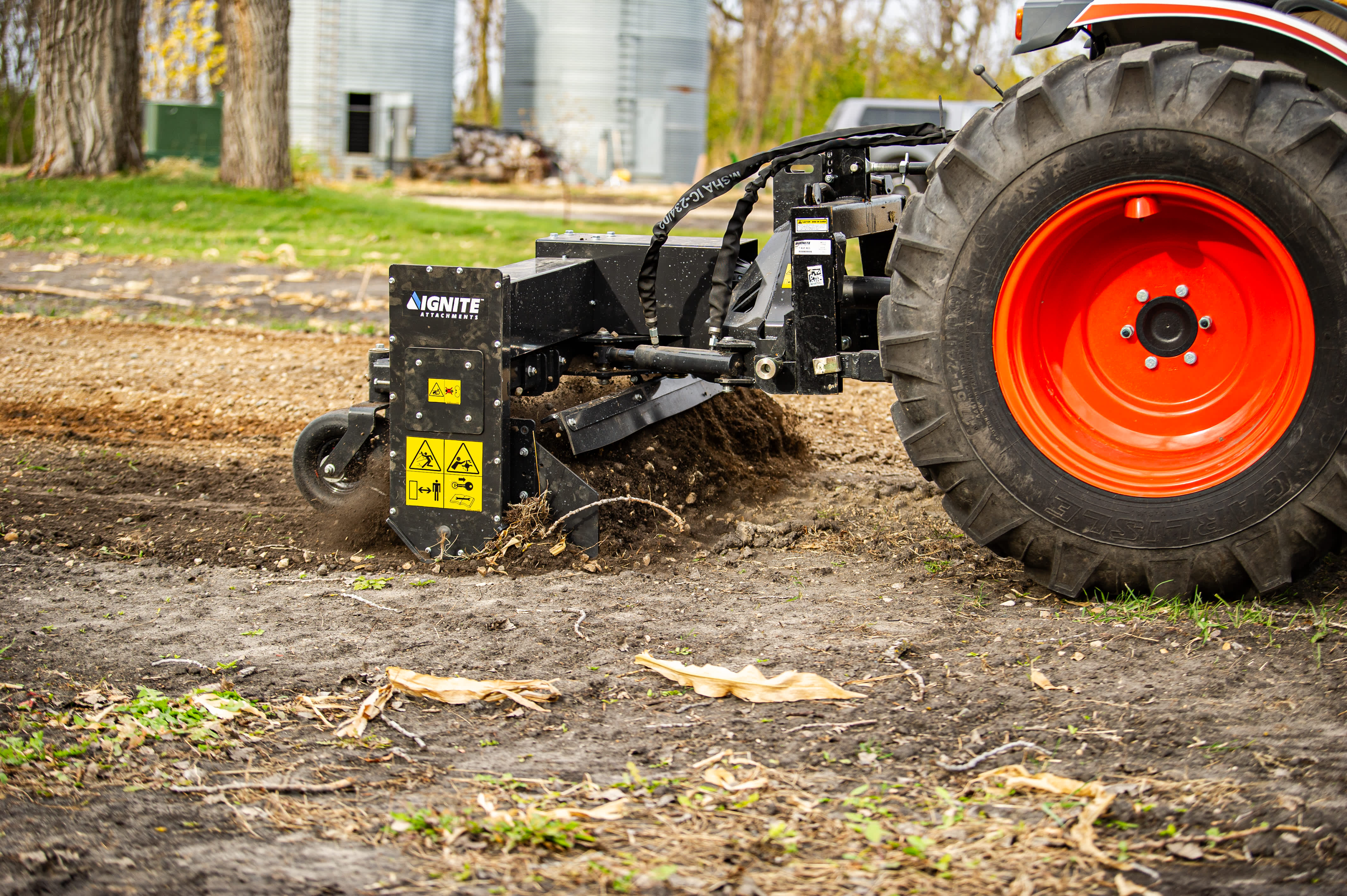 Agrimute wood chipper attached to tractor with red wheel on farm property