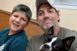 Man and boy smiling with black and white dog indoors