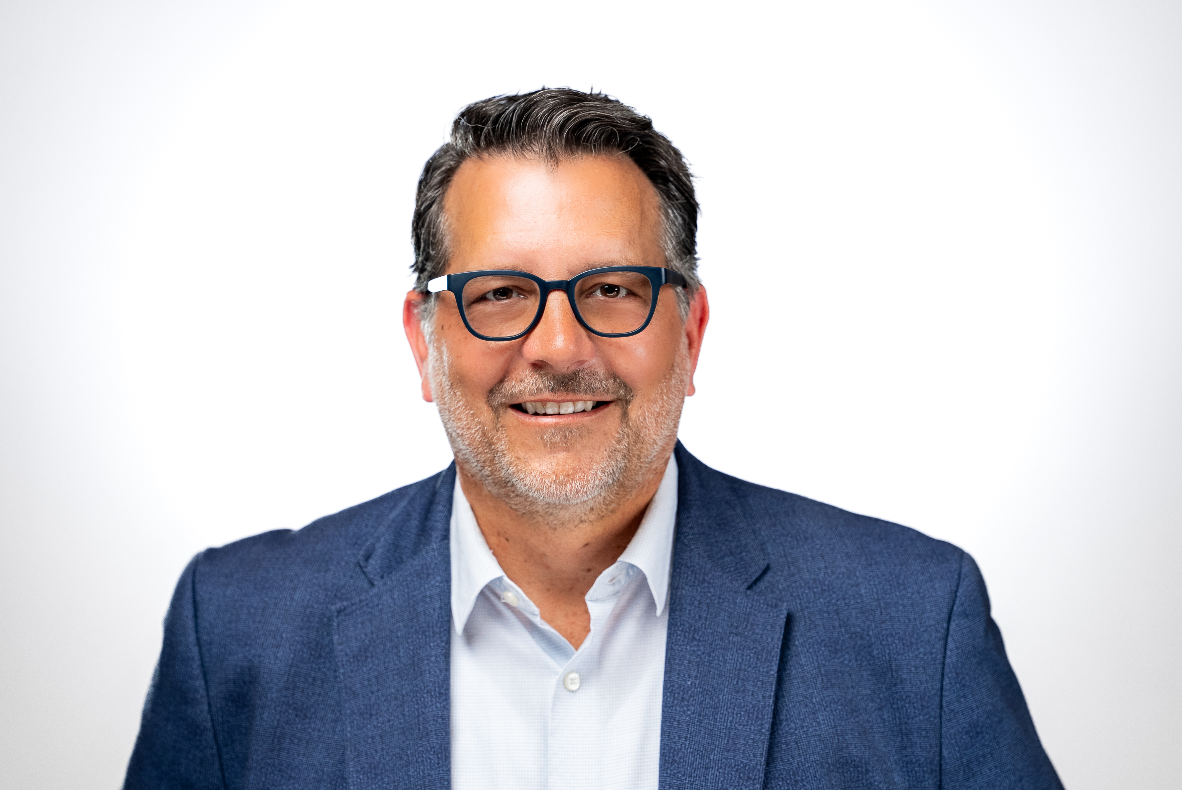 Professional headshot of a man wearing glasses and blue blazer against white background Headshot