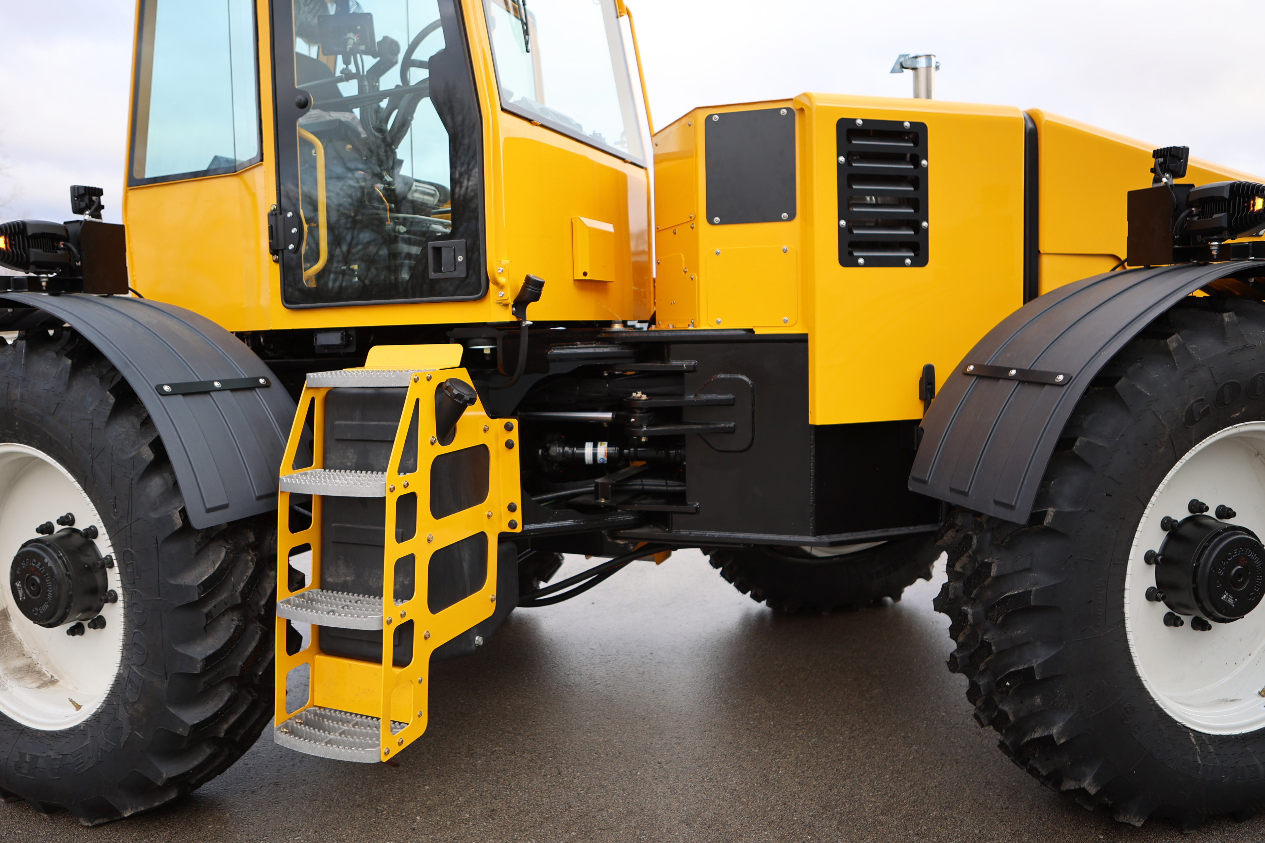 Yellow and black articulated industrial dump truck with large tires and metal access ladder on asphalt surface